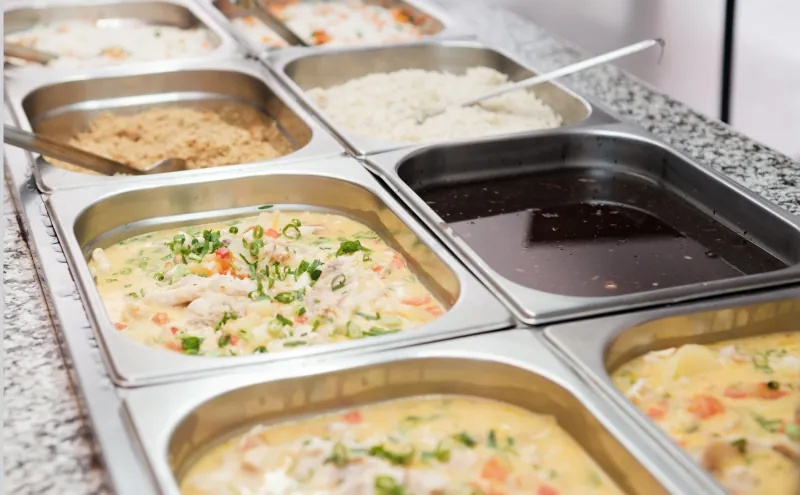 Pratos quentes servidos em cubas de inox, com ensopado de peixe e legumes, feijão e farofa, no buffet do Residencial Menino Deus